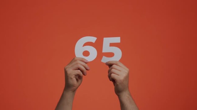 六十五号在手。显示数字的人，65岁，由雕刻纸制成，用于投票或数学学习