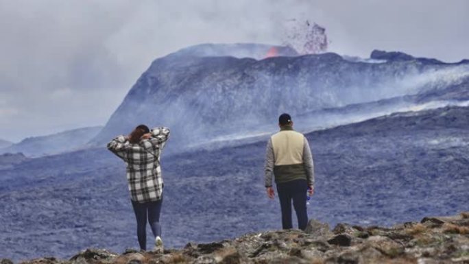 两名旅行者在岩石地上，可以看到火山爆发