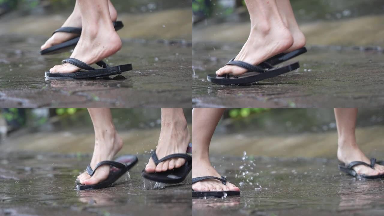 下雨天脚踩在水坑上的低角度脚，在街道上淹没水，享受飞溅的脏水，跳来跳去，热带雨季