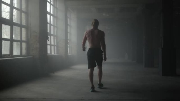走在黑暗走廊上的男人剪影。锻炼后休息的运动员