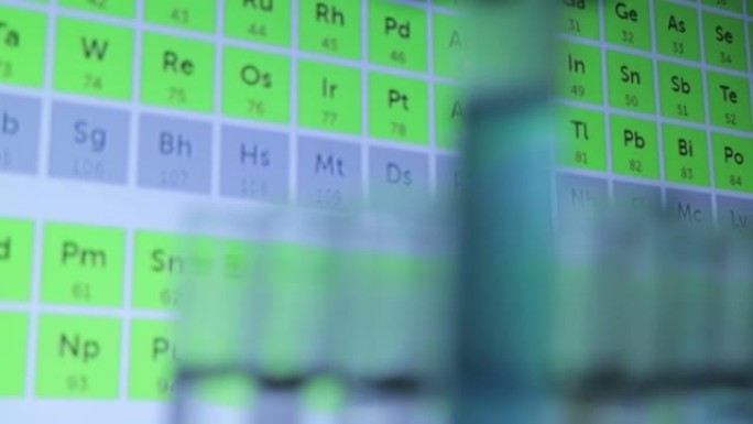 玻璃试管和研究人员的手。科学家对物质和元素的相互作用进行了研究。背景中的周期表。