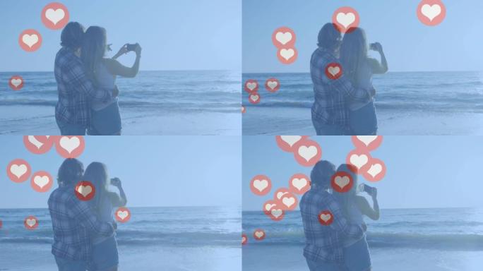 多个红色的心脏图标漂浮在白人夫妇在海滩上拍照