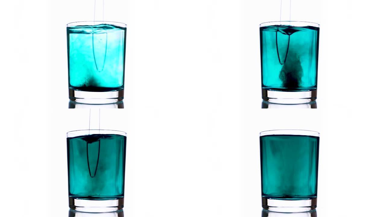 使用玻璃棒在纯净水玻璃中混合青色涂料