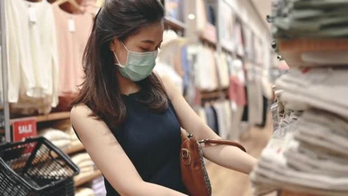 新常态的日常生活方式购物理念，年轻的亚洲女性戴着防护口罩搜索购物一家服装店许多关闭的商店小企业将在情