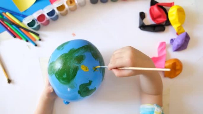 用气球为地球日做地球的孩子。用绿色大陆画蓝色球。保护环境，拯救我们的星球。生态学概念。艺术学习教育爱