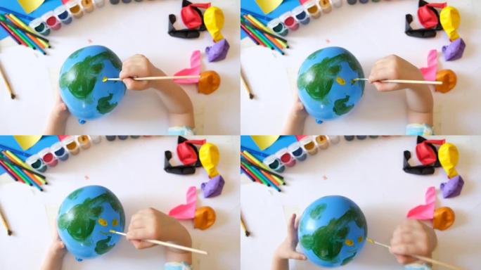 用气球为地球日做地球的孩子。用绿色大陆画蓝色球。保护环境，拯救我们的星球。生态学概念。艺术学习教育爱