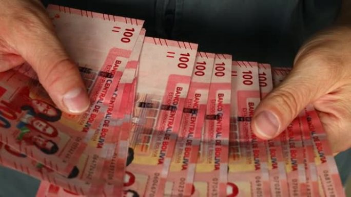 数数玻利维亚的钱，大量的100玻利维亚诺钞票，特写。财务概念