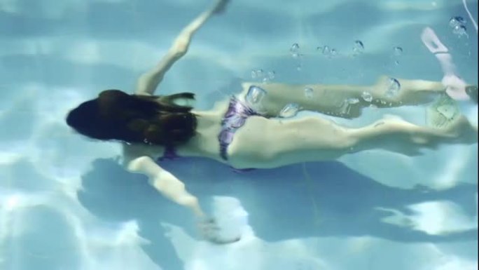 穿着露背泳衣在游泳池里水下游泳的女孩的鸟瞰图。
