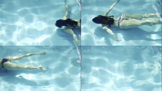 穿着露背泳衣在游泳池里水下游泳的女孩的鸟瞰图。