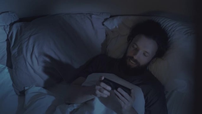 夜间电影人在床上看手机有趣的视频