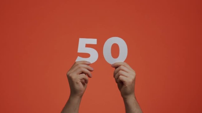 手中的五十号。显示数字的人，50个由雕刻纸制成的数字，用于投票或数学学习