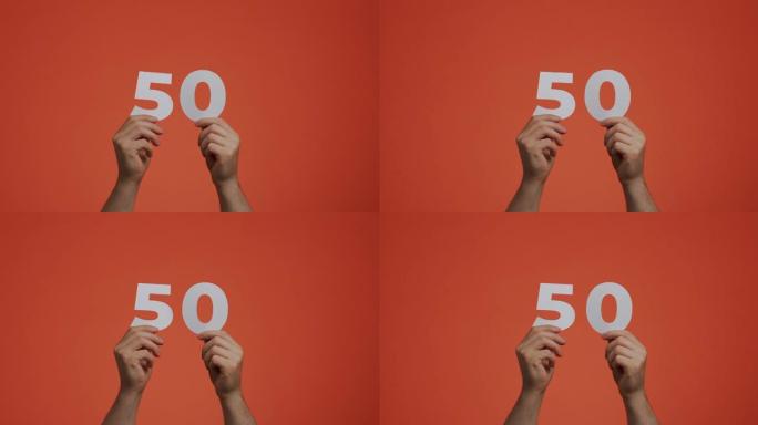 手中的五十号。显示数字的人，50个由雕刻纸制成的数字，用于投票或数学学习