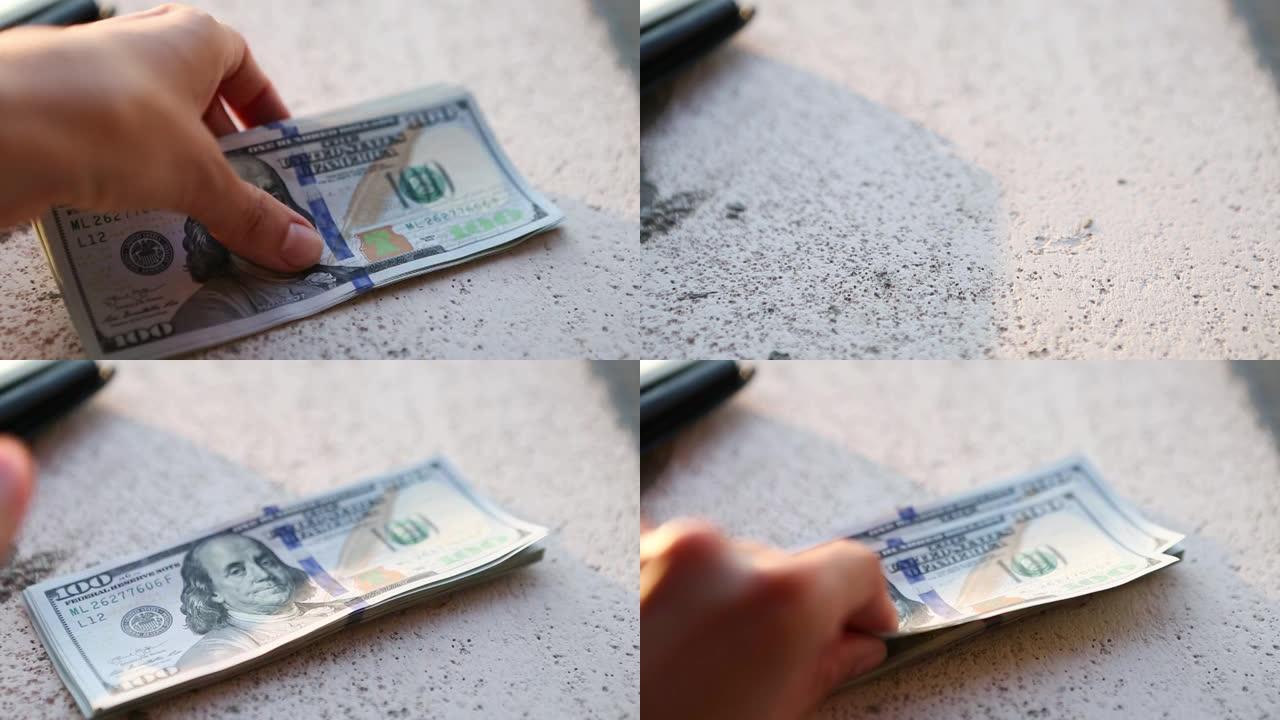 手将一百美元的钞票堆成一堆，然后拿一张钞票。现金，一叠100美元的钞票特写。金融，经济，金融规划，经