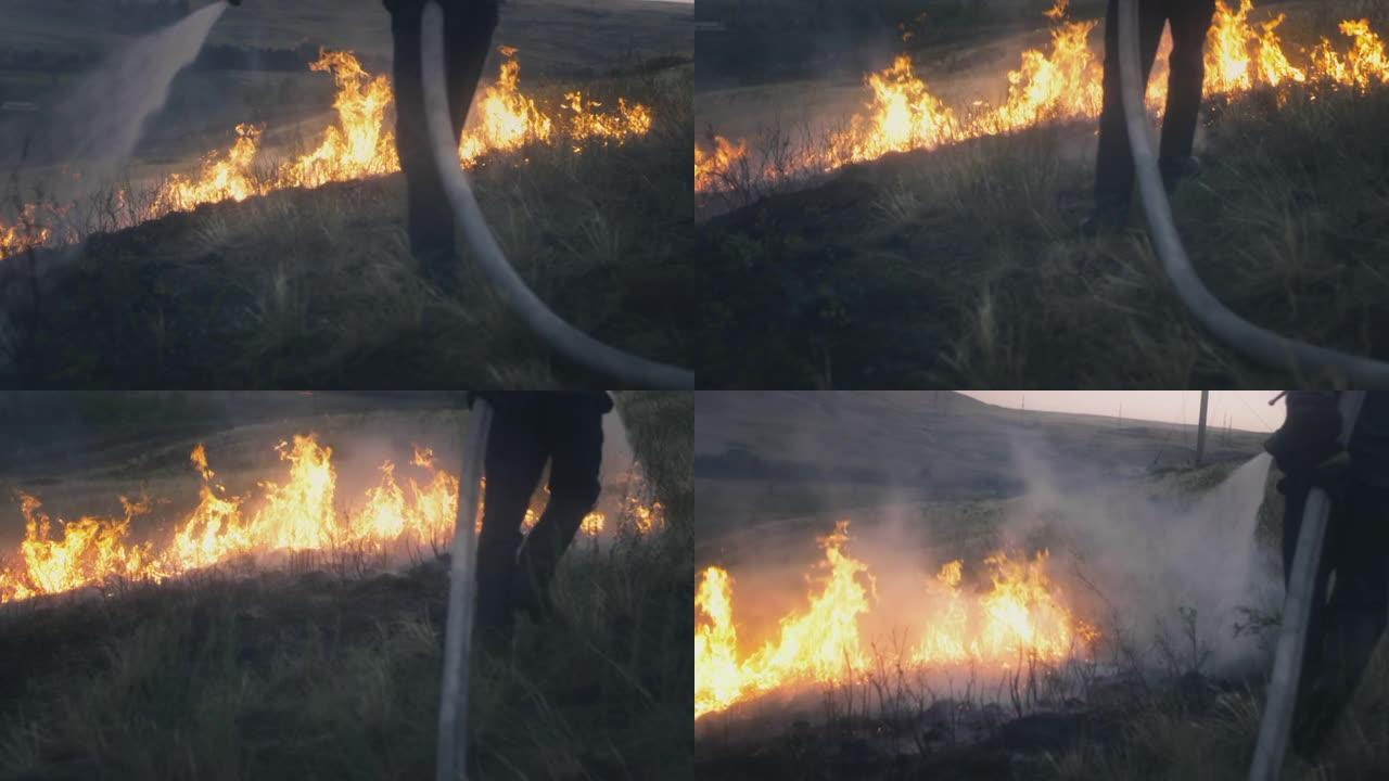 一名消防队员手中拿着一根水管，扑灭了燃烧的火焰。大自然在燃烧:草地、草原、森林和田野