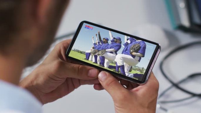 在智能手机上观看covid 19期间观看棒球比赛的男医生的合成