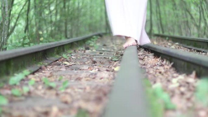 一个年轻女孩赤脚走在铁路上。