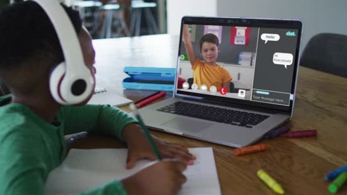 小学生在家中使用笔记本电脑进行在线课程，男孩在屏幕上进行手提和网络聊天