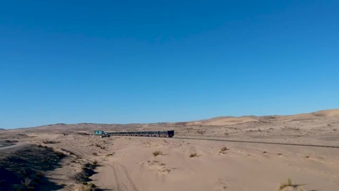 沙质沙漠景观中的铁轨上的货物列车