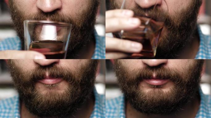 大胡子的人正在喝威士忌。男性的手把杯子拿到嘴里，喝威士忌。特写