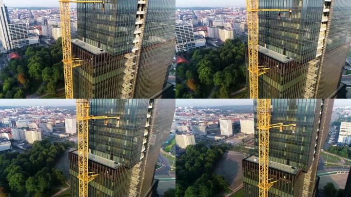 现代，在建的高层玻璃建筑，鸟瞰图。在欧洲城市建造商业摩天大楼。施工现场的高塔起重机。