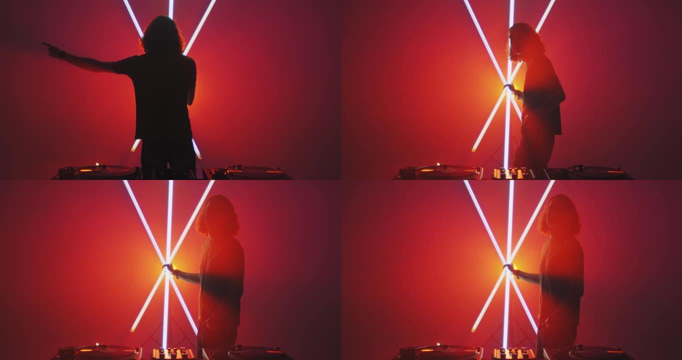 Deejay酷男在夜总会的dj控制台附近用霓虹灯表演。音乐现代锐舞概念