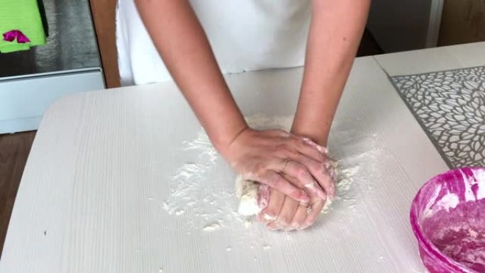 一个女人用手揉面团做饺子。用土豆和肉末煮饺子。