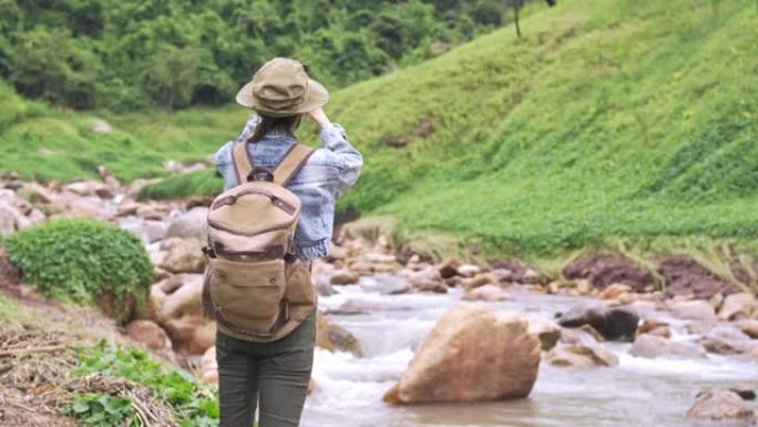 4k亚洲女性背包客在溪边的山路上徒步旅行