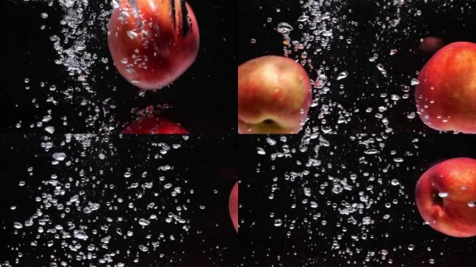成熟的红色油桃在黑色背景下落入水中