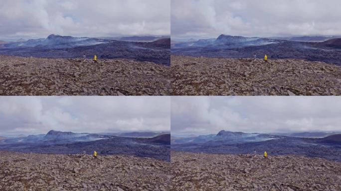 旅行者站在远处山脉的岩石视野之上
