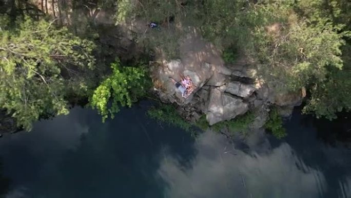 事业。一男一女躺在一块有湖的岩石上。鸟瞰图。