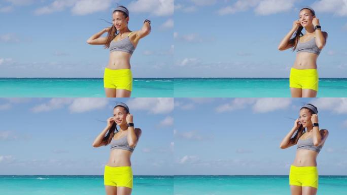跑步女孩戴着耳机和跑步臂章电话臂带准备跑步锻炼。在阳光明媚的海滩暑假锻炼时戴上耳机听音乐的手势。
