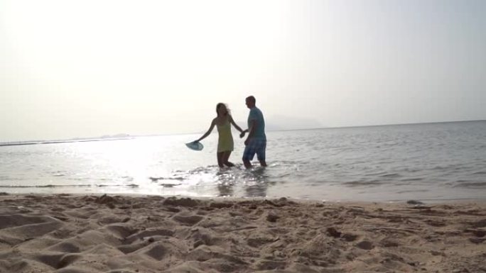 浪漫的情侣在海边日落牵着手在海滩上奔跑。爱与幸福的概念