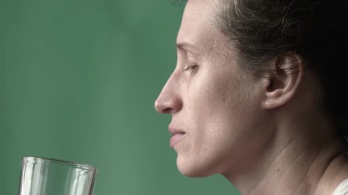 女人在喝水。女性的手将装有清水的玻璃杯带到嘴里，闭着眼睛喝。特写。高质量全高清镜头。25FPS，缩小