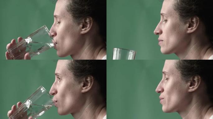 女人在喝水。女性的手将装有清水的玻璃杯带到嘴里，闭着眼睛喝。特写。高质量全高清镜头。25FPS，缩小