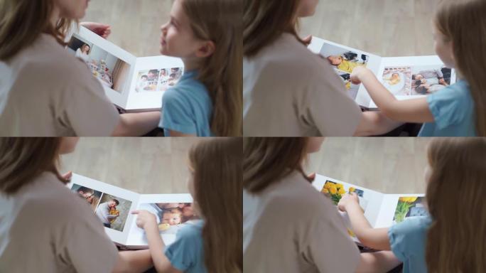 顶视图。母女看起来的书与家庭照片拍摄的照片