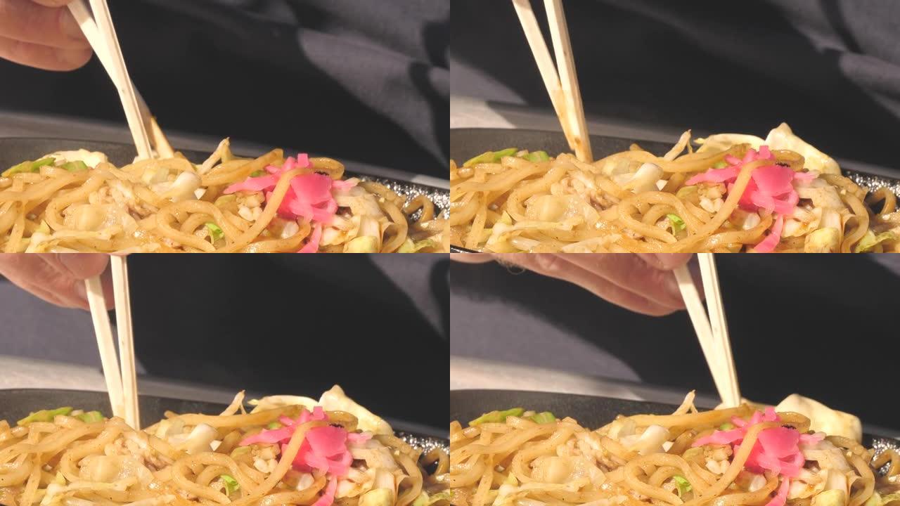 在日本，一名使用筷子吃面条的人