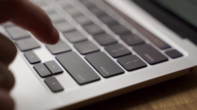 现代笔记本电脑键盘上手指按下回车键的特写。男子按下笔记本上的输入按钮