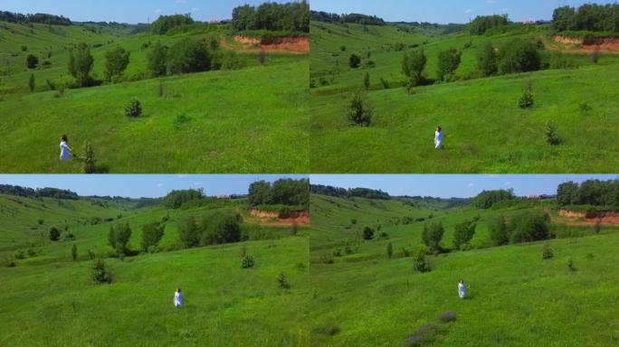一个女人在绿野的航拍。一个年轻女孩在山上散步和采花。无人机飞越人与自然。夏天快乐。享受这一刻。