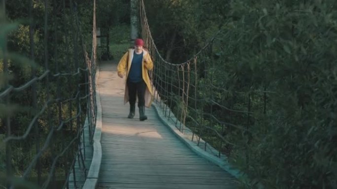 穿着黄色雨衣徒步旅行的游客沿着木制吊桥行走