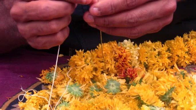 一个人制作花环和装饰辫子结或花，叶子或其他材料的花环的稳定镜头。