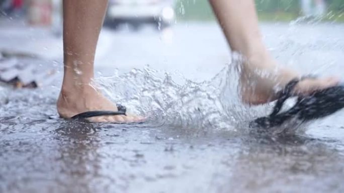 低角度的脚和脚蹼踢水在路边飞溅，大雨天，洪水泛滥的街道，玩得开心，享受雨水和水的玩耍，关闭下半身，天