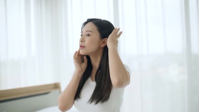 专注的年轻亚洲女性在镜子前化妆