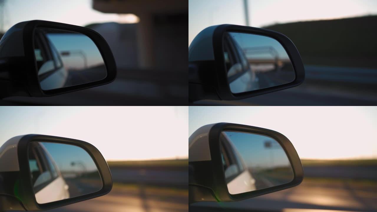 在日落灯光下在高速公路上快速行驶的侧镜车中观看。