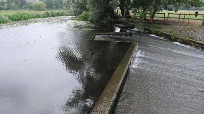 快速流动的水流过堰。萨福克郡萨德伯里斯托尔河上的水上草地