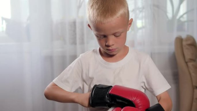 一个小男孩在家里戴上拳击手套。