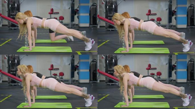 苗条身材的白人女运动员站在健身房的板形体垫上的侧视图。两个自信的年轻美女在室内锻炼。运动和锻炼概念
