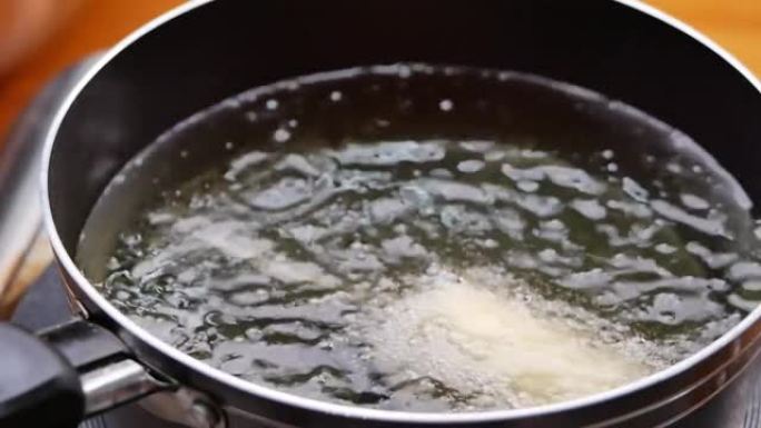 香肠串涂上面糊，用热油在厨房炉子上的平底锅里油炸。自制玉米狗。烹饪过程。