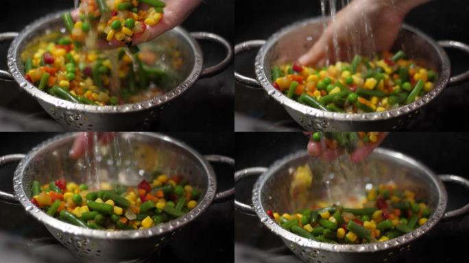 雌性手洗黄瓜辣椒粉番茄青豆玉米番茄辣椒花椰菜胡萝卜。慢动作用水手洗新鲜切碎的蔬菜。素食有机保健食品。