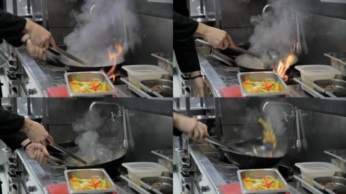 厨师的手在煤气炉火焰上用炒锅炒菜，用钢包搅拌