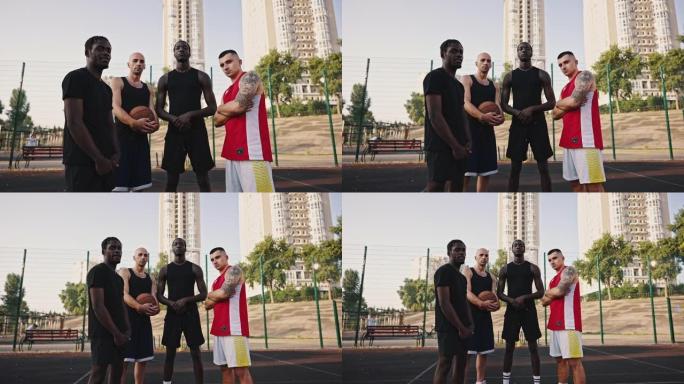篮球队。缩小篮球场上多民族运动员团队的肖像。穿着运动服和篮球的高加索人和非洲人朋友